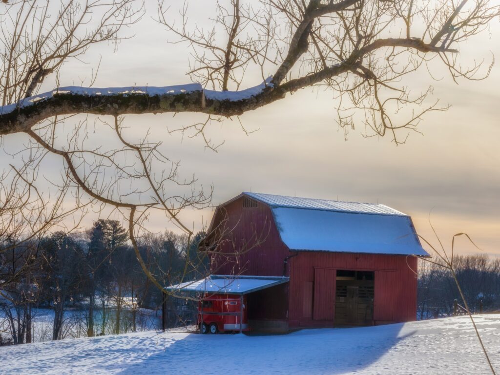Rural landscape in winter with barn and metal roofing in the foreground