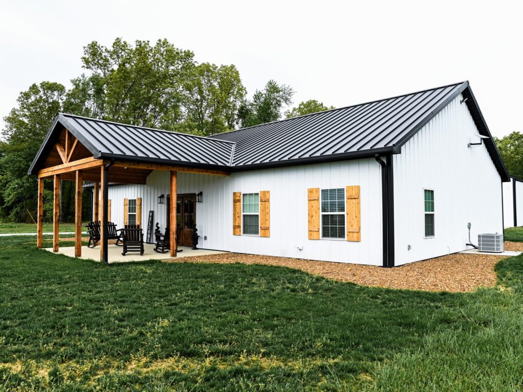Close up photo of white barndominium with black metal roofing.